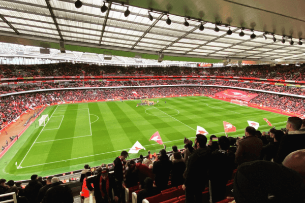 Inside the Emirates Stadium during a football match, with players on the field and fans in the stands.