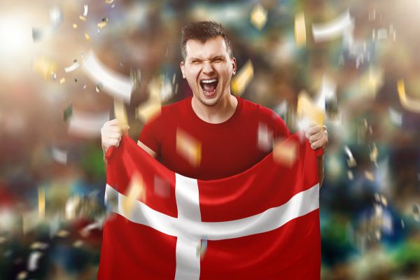 Man holding a Danish flag, celebrating with joy.