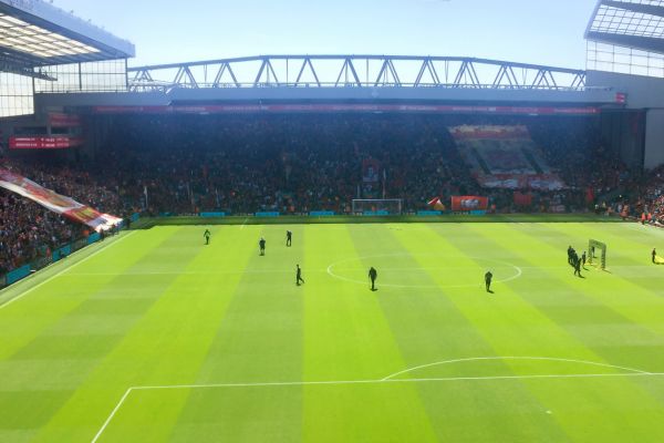 The Kop at Anfield, filled with passionate Liverpool fans, as seen from the opposite end of the stadium during a match day