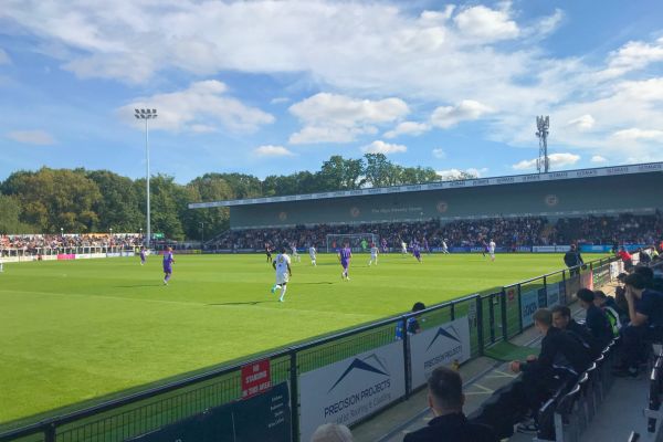 Football match at Hayes Lane Stadium, home of Bromley FC, with fans in attendance.