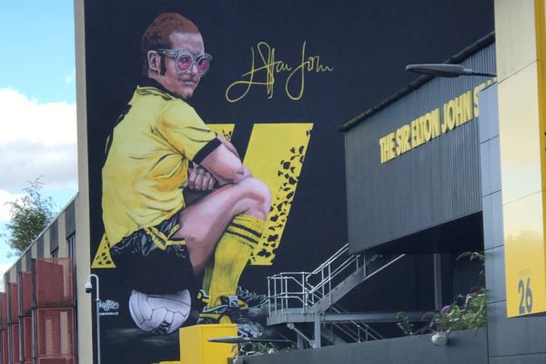 Mural of Sir Elton John in Watford colors seated on a football at Vicarage Road