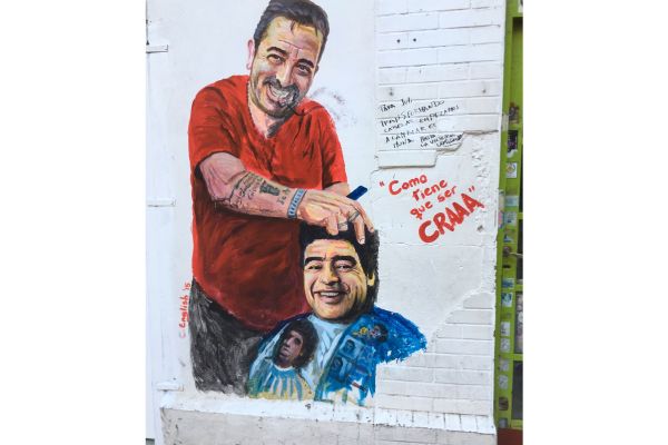 Humorous mural of Diego Maradona getting a haircut, painted on the wall outside a barber shop in Villa Crespo, Buenos Aires.