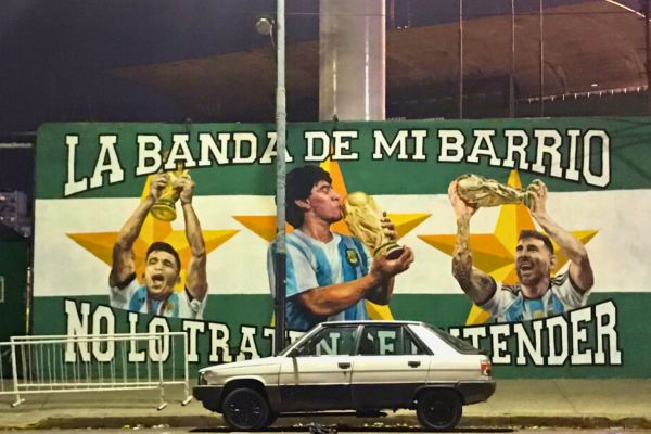 Mural of Lionel Messi and Diego Maradona holding World Cups outside the Ferro Carril Oeste stadium, celebrating Argentina’s football legends.