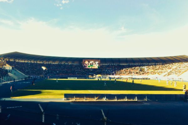 A soccer match featuring Real Potosí at Estadio Ramón Tahuichi Aguilera, one of the highest stadiums in the world, with players in action on the green field under a clear sky.