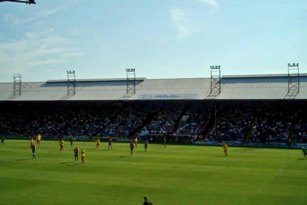 Football match in action at Selhurst Park Stadium, home of Crystal Palace FC, with fans filling the stands.