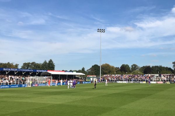 Notts County players in their modern away kit competing against Bromley FC players in white with red trim on a well-maintained football pitch at Bromley’s home ground, surrounded by a modest crowd.