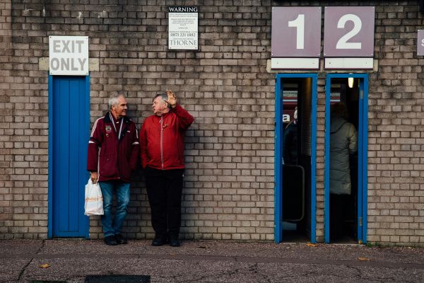 Fans standing near the turnstile entrances at Turf Moor, ready to support Burnley FC.