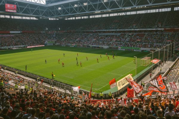 A vibrant view of Merkur Spiel Arena in Düsseldorf filled with fans on a matchday, showcasing the illuminated stadium and its colorful seating.