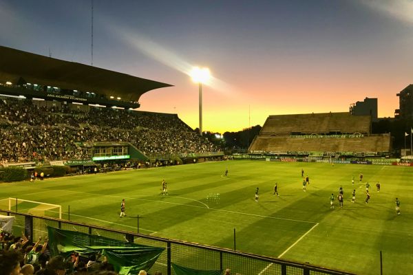 Nighttime football match under floodlights at Ferro Carril Oeste Stadium in Buenos Aires, featuring teams Ferro Carril Oeste and Almirante Brown.