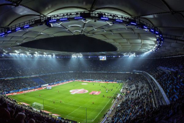 Hamburg stadium interior during a nighttime match, illuminated with fans in the stands.