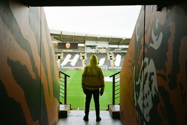 A stadium security guard standing at the entrance to a stand at a stadium.