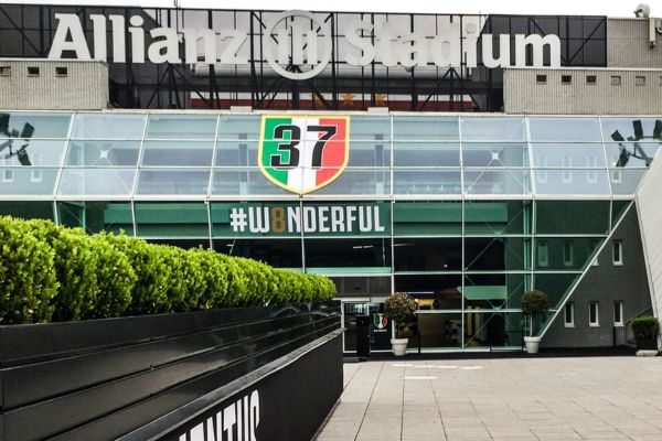 The main entrance of the Allianz Arena featuring Juventus branding, with sleek modern architecture illuminated by lights.