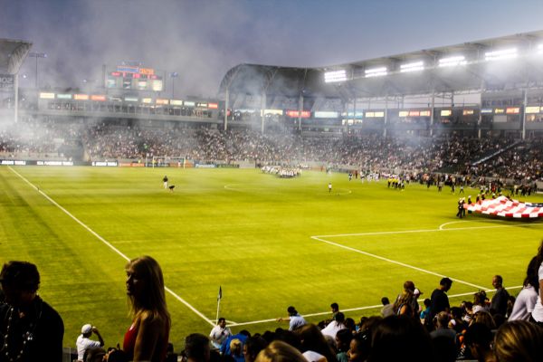 Matchday at the LA Galaxy stadium under floodlights, with fans cheering and players on the field.