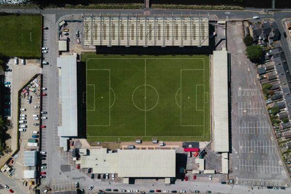 An aerial view of Lincoln City Stadium, showcasing its compact layout, green pitch, and surrounding urban landscape in Lincoln, England