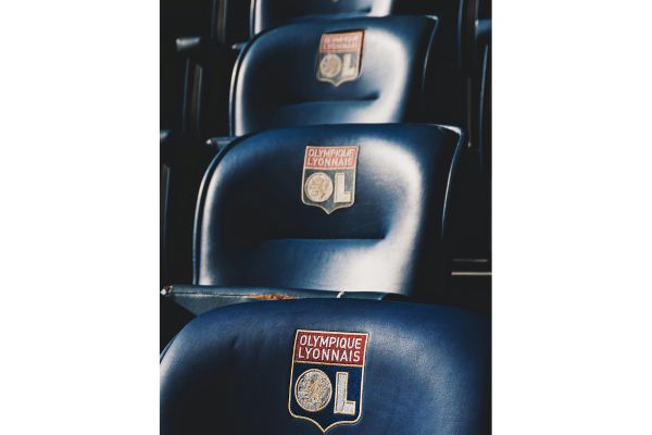 Blue seats with the Olympique Lyonnais club badge at Groupama Stadium.