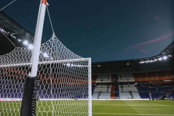 View from behind the goal at Olympique Lyonnais’ stadium under floodlights.