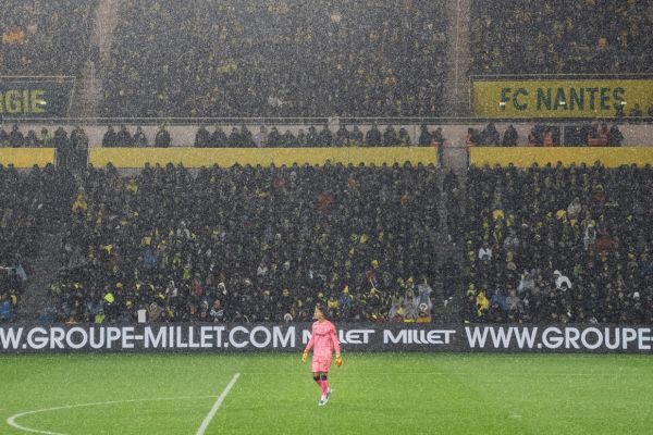 Fans in the stands at Nantes FC’s Stade de la Beaujoire, watching a rainy match unfold.