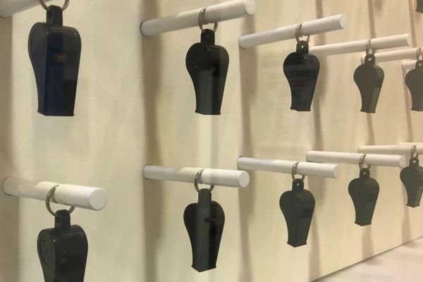 Referee whistles hanging on display at Loftus Road Stadium, showcasing the evolution of this essential football officiating tool.