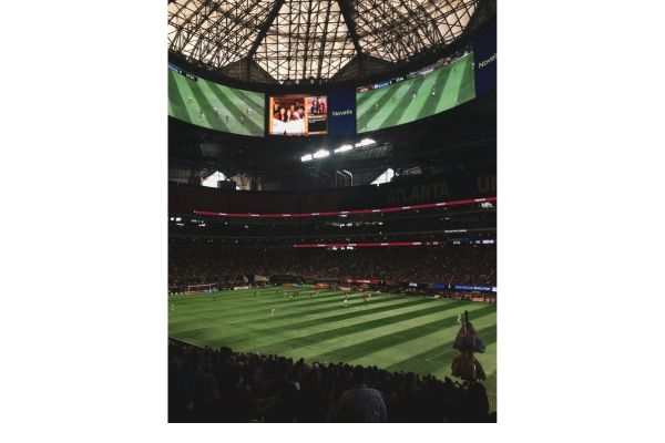 Interior view of Mercedes-Benz Stadium during a match, featuring the vibrant crowd and the large Halo Board screen displaying game highlights.