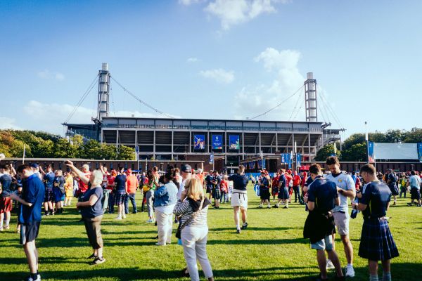 Scotland football fans gathered outside Cologne FC stadium, waving flags and wearing team merchandise.