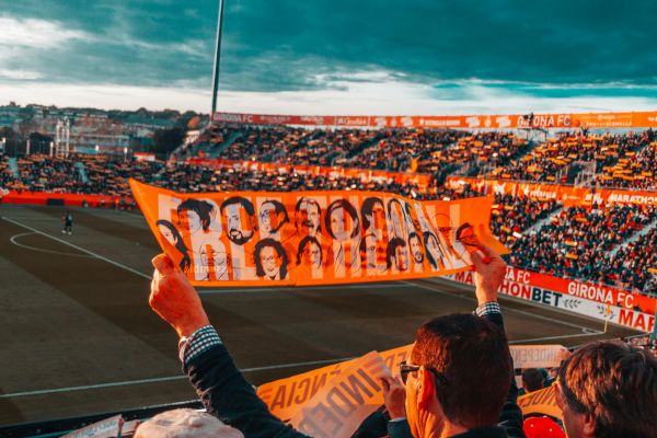 Fans cheering passionately at Estadi Montilivi during a Girona FC match, creating a lively and energetic atmosphere.