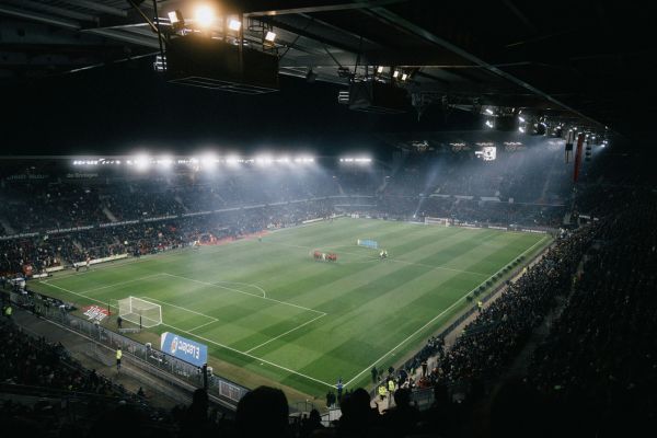 Roazhon Park illuminated on a matchday evening, with a vibrant crowd and glowing stadium lights highlighting the electric atmosphere.