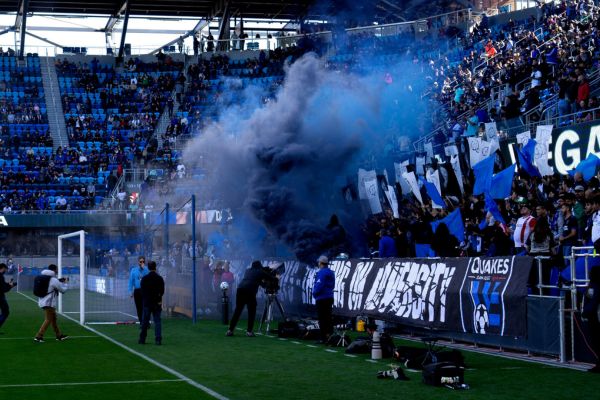 Fans at PayPal Park letting off blue smoke flares during a matchday, creating an electric atmosphere.