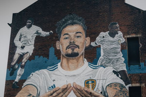 Mural of Leeds United players on a brick wall.