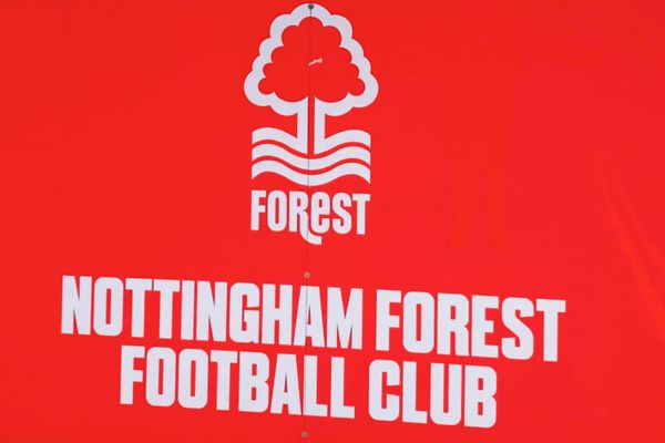 Photo of sign outside City Ground Stadium of Nottingham Forest Football Club and Badge painted onto wall.
